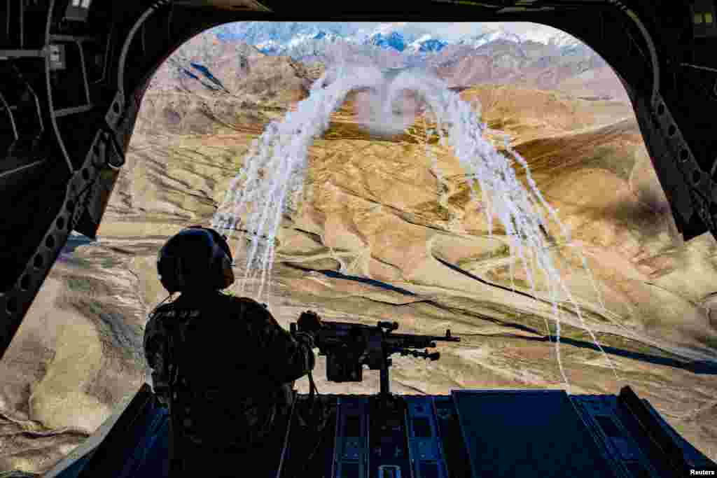 A U.S. Army crew chief flying on board a CH-47F Chinook helicopter observes the successful test of flares during a training flight in Afghanistan, March 14, 2018. (Photo courtesy: U.S. Air Force/Tech. Sgt. Gregory Brook/Handout via Reuters)