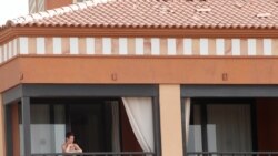 Una mujer observa desde la ventana de la habitación del hotel donde las autoridades españolas los mantienen encerrados debido a dos casos positivos del nuevo virus.