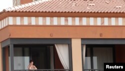 Una mujer observa desde la ventana de la habitación del hotel donde las autoridades españolas los mantienen encerrados debido a dos casos positivos del nuevo virus.