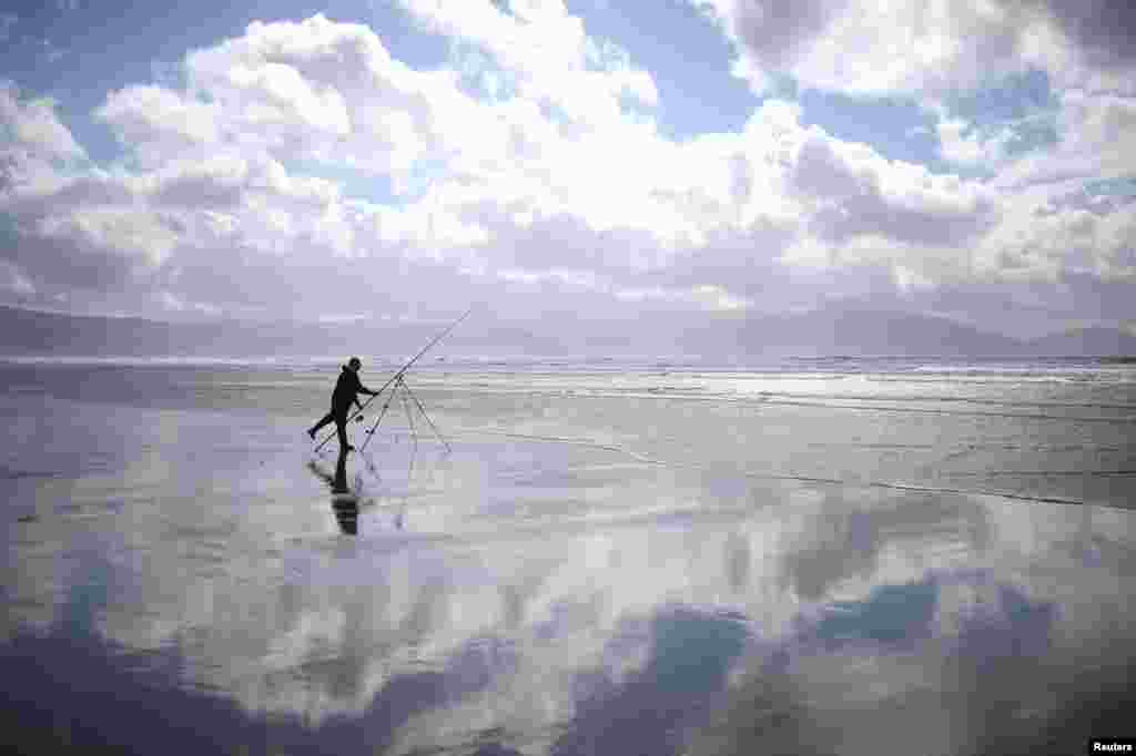 A man participates in the Diawa Irish Pairs sea angling event in windy conditions on the Dingle Peninsula of Inch beach in Inch, Ireland.