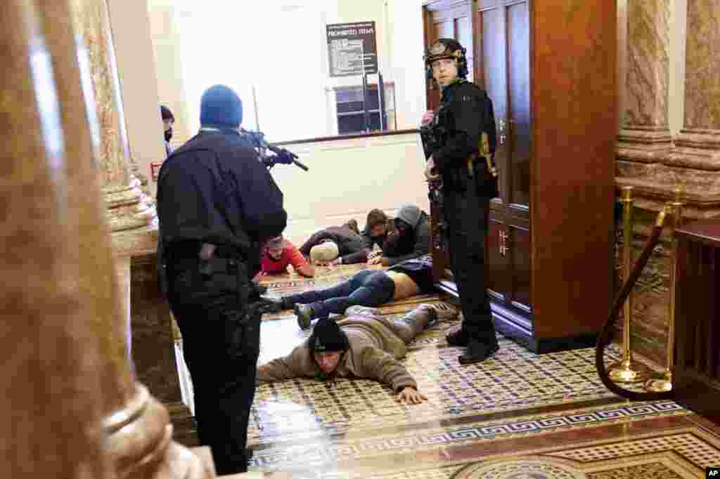 A Polícia do Capitólio dos EUA mantém manifestantes sob a mira de armas perto da Câmara dos Representantes, dentro do Capitólio dos EUA, na quarta-feira, 6 de Janeiro de 2021, em Washington. (AP Photo/Andrew Harnik)