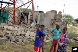 Children look at a damaged telecommunications mast after an attack by al-Shabab extremists in the settlement of Kamuthe in Garissa county, Kenya Monday, Jan. 13, 2020.