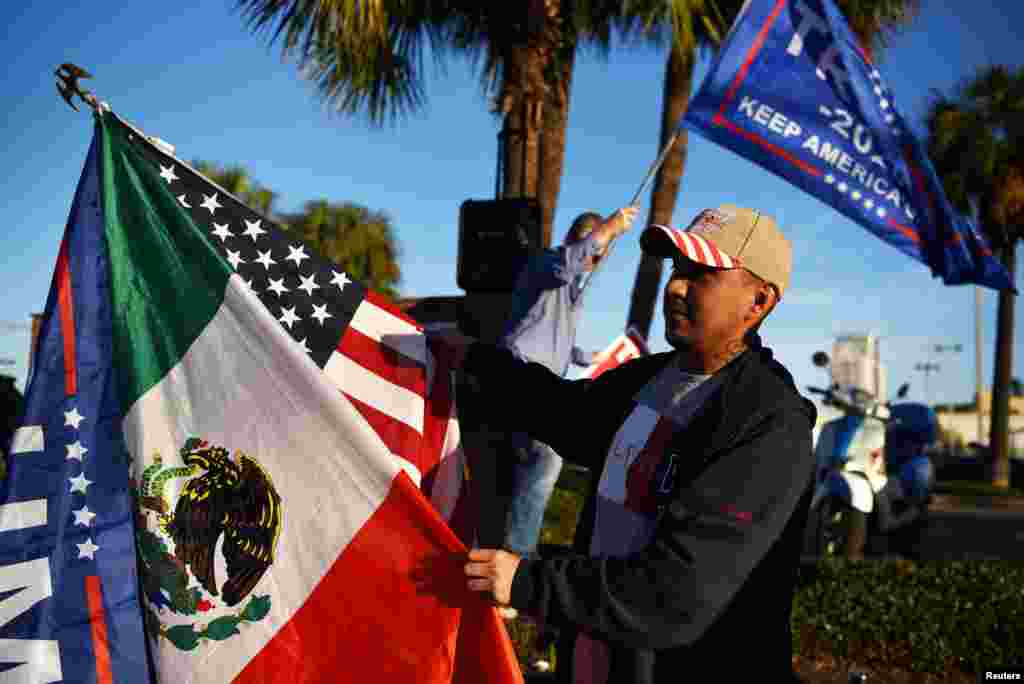 Jos&#233; Casares, de 32 a&#241;os, agita banderas en apoyo de Trump mientras algunos votantes se alinean en un colegio electoral durante el d&#237;a de las elecciones en Houston, Texas.
