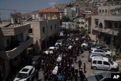 Para pelayat dari kelompok minoritas Druze membawa peti jenazah dari sekitar 12 anak-anak dan remaja yang tewas dalam serangan roket di lapangan sepak bola di Dataran Tinggi Golan yang dianeksasi Israel, Minggu, 28 Juli 2024. (Foto: AP)