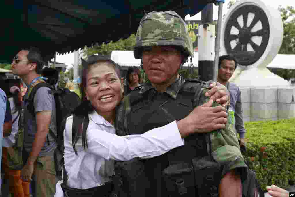A pro-government demonstrator embraces a Thai soldier during a cleanup operation at a pro-government demonstration site, on the outskirts of Bangkok, May 23, 2014.