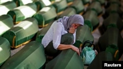 A Bosnian woman cries at a coffin of her relative, one of 173 coffins of newly identified victims from the 1995 Srebrenica massacre, in the Potocari Memorial Center, near Srebrenica, July 9, 2014. 