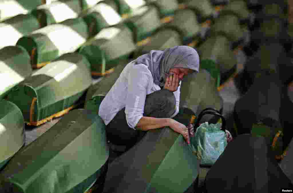 A Bosnian woman cries at a coffin of her relative, one of 173 coffins of newly identified victims from the 1995 Srebrenica massacre, in the Potocari Memorial Center, near Srebrenica.