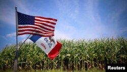 FILE - U.S. and Iowa state flags are seen next to a cornfield in Grand Mound, Iowa, Aug. 16, 2015. 