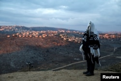 A Jewish man covered in a prayer shawl, prays in the Jewish settler outpost of Amona in the West Bank, Dec. 18, 2016.