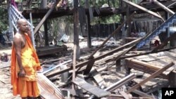 A Cambodian Buddhist monk watches a house damaged by a rocket during Monday night's armed clash near the disputed border area between Cambodia and Thailand in Kork Morm village, Udor Meanchey province, Cambodia, Tuesday, April 26, 2011. Thai and Cambodian