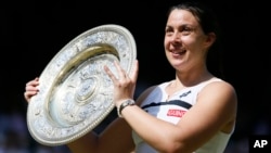 Marion Bartoli of France poses with the trophy after winning against Sabine Lisicki of Germany in the Women's singles final match at the All England Lawn Tennis Championships in Wimbledon, London, July 6, 2013.