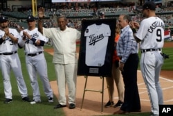 Pedro Sierra, pitcher for the Negro Leagues' Detroit Stars and Indianapolis Clowns from 1954-1958 receives a Tigre's baseball jersey during a pre-game ceremony, Aug. 12, 2017, in Detroit.