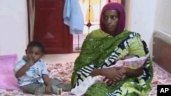 FILE - Meriam Ibrahim, sitting next to Martin, her 20-month-old son, holds the newborn daughter she gave birth to in jail in May at a prison in Khartoum, Sudan. 