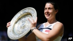 Marion Bartoli dari Perancis berpose dengan trofi kejuaraan Wimbledon setelah mengalahkan Sabine Lisicki dari Germany dalam final putri di London (6/7). (AP/Stefan Wermuth)