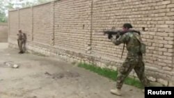 A member of Afghan security forces fires towards Taliban positions on a street in Kunduz, Afghanistan, Aug. 31, 2019, in a still image taken from video.