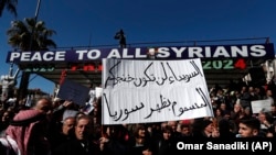 FILE - Syrian Druze hold up a placard in Arabic which reads "Sweida will not be your poisoned dagger in Syria's back" and stage a demonstration against Israeli incursions into Syrian territory in the southern province of Sweida, Syria, Feb. 25, 2025.