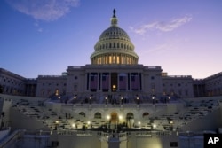 FILE - The sun rises behind the U.S. Capitol as a rehearsal begins on the West Front ahead of President-elect Donald Trump's upcoming inauguration in Washington, Jan. 12, 2025.