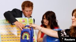 Britain's Prince Harry is shown a wind up radio by UNICEF personnel Alison Tilbe (C) and Hilde Johnson at UNICEF offices during his visit to New York June 26, 2010.