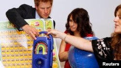 Personil UNICEF Alison Tilbe (tengah) dan Hilde Johnson memperlihatkan sebuah radio putar (wind up radio) kepada Pangeran Harry dari Inggris saat berkunjung di kantor UNICEF, New York, 26 Juni 2010. (Foto: dok).