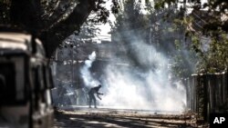 A Kashmiri protester throws an exploded tear smoke shell on government forces during a clash following the killing of two suspected rebels in a gunfight with government forces in Srinagar, Indian controlled Kashmir, Oct. 12, 2020. 