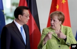 FILE - German Chancellor Angela Merkel and Chinese Premier Li Keqiang talk during a contract signing ceremony as part of a meeting at the chancellery in Berlin, June 1, 2017.