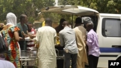 Офицеры полиции и врачи эвакуируют жертв взрывов и стрельбы в Кано, Нигерия