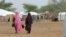 FILE - Malian women walk in a refugee camp in Burkina Faso, July 26, 2013. Violence caused by suspected Islamist attacks has forced tens of thousands of people within Burkina Faso to flee their homes.