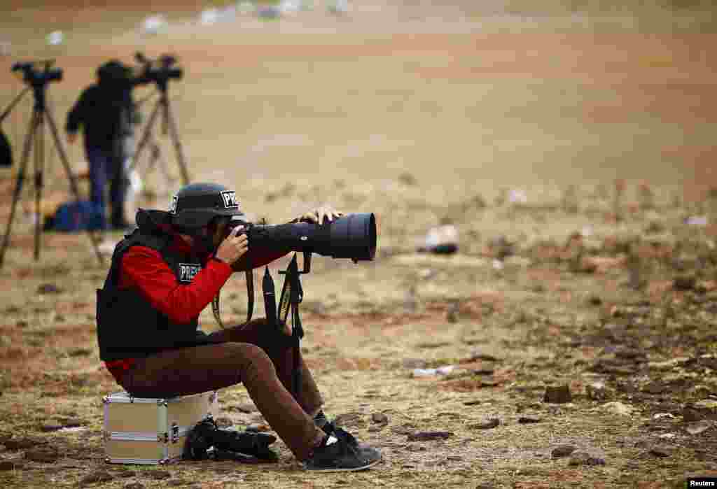 A news photographer takes pictures of the Syrian town of Kobani from near the Mursitpinar border crossing, on the Turkish-Syrian border in the southeastern town of Suruc.