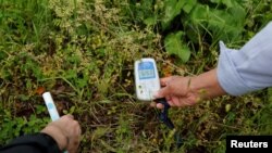 Tour guide Katsuaki Shiga, right, and a tourist check radiation levels at Joroku Park, near Tokyo Electric Power Co.'s tsunami-crippled Fukushima Daiichi nuclear power plant, in Namie town, Fukushima prefecture, Japan, May 17, 2018. 