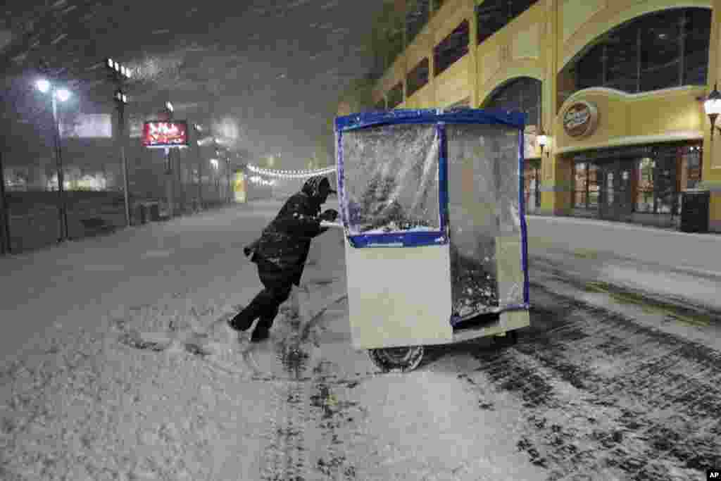 A man maneuvers his push cart with passengers during a snowstorm early Saturday, Jan. 23, 2016, on the Atlantic City Boardwalk in New Jersey. Most of the U.S. East Coast face a blizzard from Friday evening until Sunday. (AP Photo/Mel Evans)