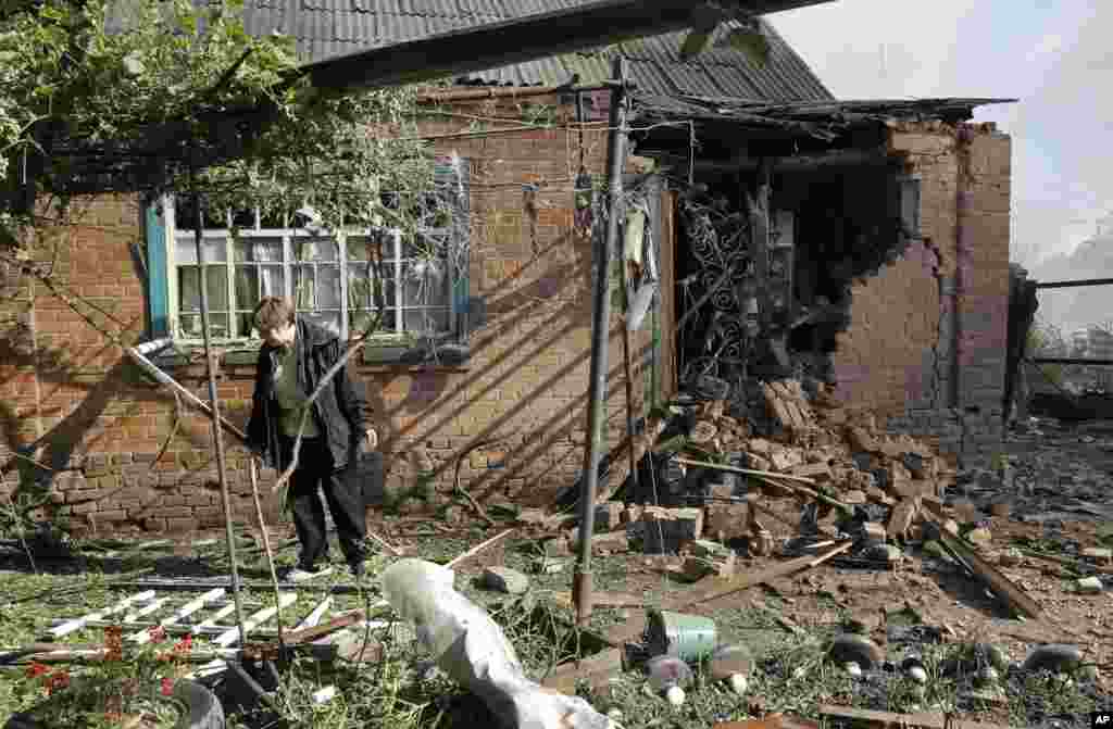 Seorang perempuan memeriksa rumahnya setelah penembakan di Slovyansk, Ukraina timur (30/6). (AP/Dmitry Lovetsky)