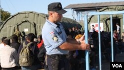 Croatian police guard a camp near the border they say will house refugees for a day or two before they are transferred to the border with Hungary, Opatovac, Croatia, Sept. 21, 2015. (VOA / H. Murdock) 