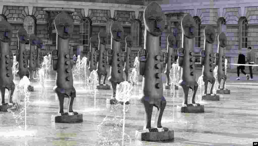 The fountains flow around an installation by artist Zak Ove, of a Nubian army of masked men as they stand in the courtyard at Somerset House in London, Oct. 4, 2016. 