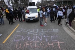 People gather in protest, Sunday, April 11, 2021, in Brooklyn Center, Minn. The family of Daunte Wright, 20, told a crowd that he was shot by police Sunday before getting back into his car and driving away, then crashing the vehicle several blocks away. T