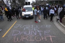 People gather in protest, Sunday, April 11, 2021, in Brooklyn Center, Minn. The family of Daunte Wright, 20, told a crowd that he was shot by police Sunday before getting back into his car and driving away, then crashing the vehicle several blocks away. T