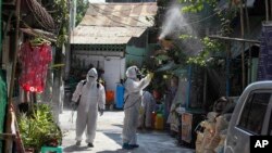 ရန်ကုန်မြို့တွင် ကိုရိုနာဗိုင်းရပ်စ် ပျံ့နှံ့မှု ကာကွယ်နိုင်ရေး နေအိမ်အချို့ကို ပိုးသတ်ဆေးဖျန်းနေသည့် စေတနာ့ဝန်ထမ်းအချို့။ (ဧပြီ ၁၄၊ ၂၀၂၀)