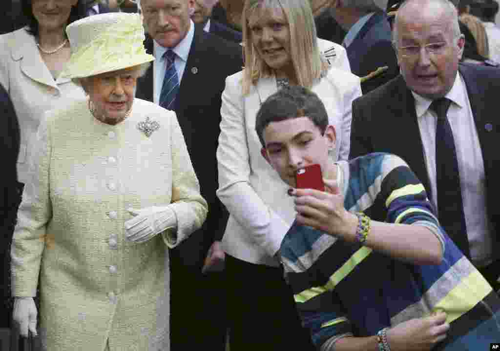 A local youth takes a selfie in front of Queen Elizabeth II during a visit to St. George&#39;s indoor market on in Belfast, Northern Ireland.