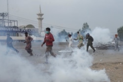 FILE - Supporters of the banned Islamist political party Tehrik-e-Labaik Pakistan (TLP) run amid the smoke of tear gas during a protest in Lahore, Pakistan, October 23, 2021.