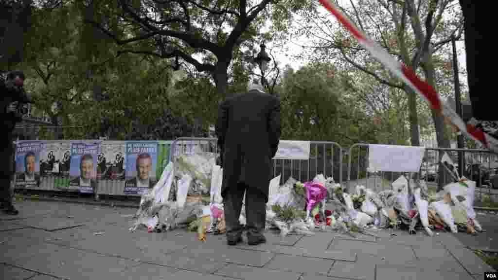 A man looks at the items left at a memorial outside the Bataclan Concert Hall a day after more than 120 people were killed in a series of attacks in Paris, Nov. 14, 2015.