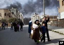 A family escapes from fierce fighting between Free Syrian Army fighters and government troops in Idlib, north Syria, March 10, 2012.