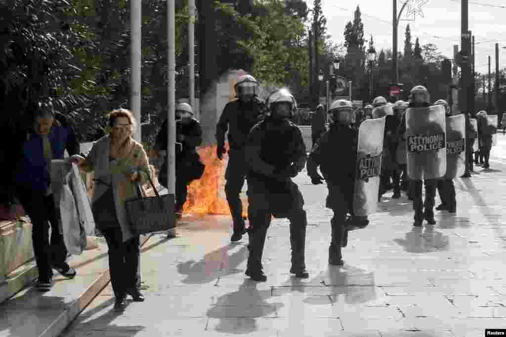 Passers-by (L) flee as a petrol bomb explodes following brief clashes between police and protesters during a protest marking a 24-hour strike in Athens, Greece. Striking workers took to the streets, disrupting transport, shutting schools and keeping ships docked at port in the second major protest against planned pension cuts in three weeks.