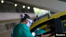 Медработник тестирует водителя такси на коронавирус. Рио-де-Жанейро, лето 2020 г. 