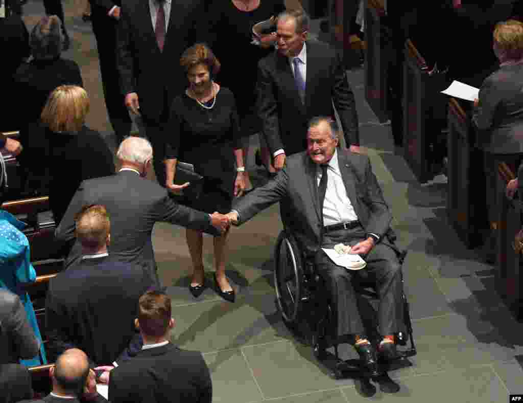 L'ancien président américain George H.W. Bush salue l’ancien vice-président Joe Biden à son départ des funérailles de sa femme, la Première Dame Barbara Bush, suivie de sa belle-fille, l'ancienne Première Dame Laura Bush et de l'ancien Président George W.