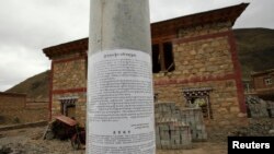 FILE - A notice about self-immolations, which offers a reward of 100,000 yuan ($16,319) for information on those "masterminding, supporting, abetting and coercing others to self-immolate," is posted in Barma township, May 16, 2013.