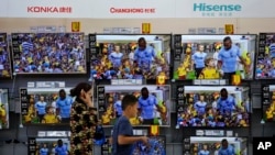 Suasana di sekitar piranti televisi dan elektronik yang dipajang di sebuah hypermarket di Beijing, 11 Juli 2018. 