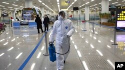 身穿防护服的朝鲜工作人员在平壤国际机场喷洒消毒水并检测旅客的体温。（2020年2月1日）