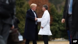 川普总统2018年1月12日在马里兰州贝塞斯达的沃尔特·里德国家军事医疗中心结束体检后，乘坐海军陆战队一号总统专用直升机前往临近的安德鲁斯联合基地之前，在飞机旁和白宫医生罗尼·杰克逊握手。