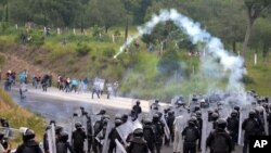 Policías antimotines lanzan gas lacrimógeno a estudiantes y manifestantes de la escuela de Ayotzinapa, para bloquearles el paso hacia Chilpancingo.
