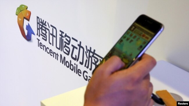 在北京举行的全球移动互联网会议上一名参观者在腾讯展台前玩智能手机上的游戏。（2015年4月28日）