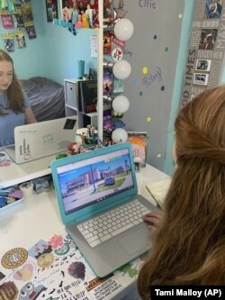 In this April 10, 2020 photo made available by Tami Malloy, Grace Malloy watches a virtual tour of the University of Colorado, while at home in Forest Grove, Oregon.